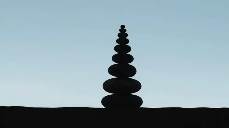 A silhouette observes a spiral while balancing stones on a horizon