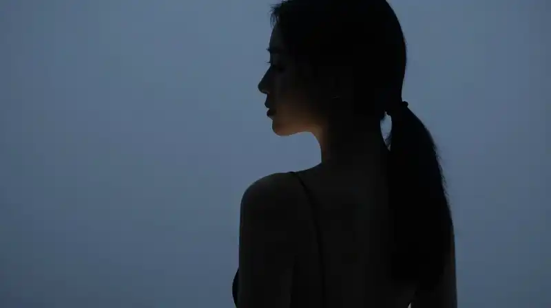 A womans silhouette is split between soft glow and shadow